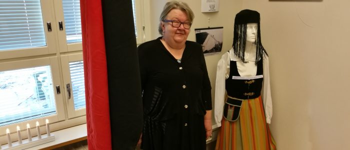 Perniön karjalaisten puheenjohtaja Maarit Leppänen Taidekahvilan näyttelyaarteiden keskellä.